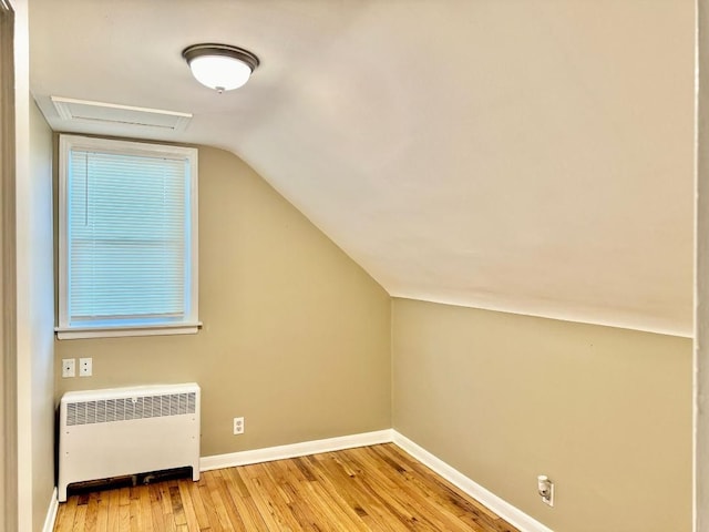 bonus room with radiator heating unit, light hardwood / wood-style floors, and vaulted ceiling