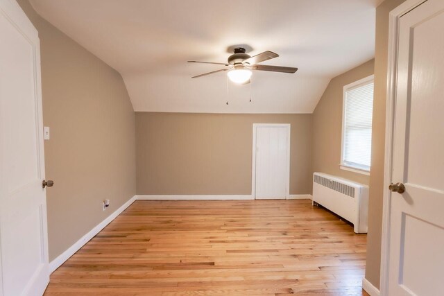 additional living space featuring radiator heating unit, light hardwood / wood-style floors, ceiling fan, and lofted ceiling