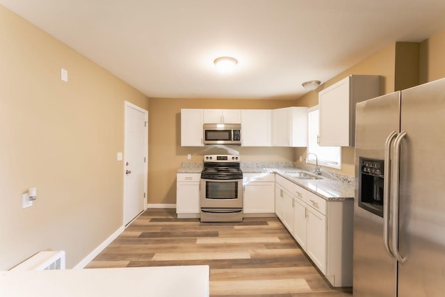 kitchen featuring white cabinets, sink, light wood-type flooring, and stainless steel appliances