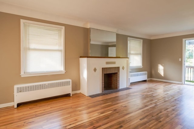 unfurnished living room featuring light wood-type flooring, a fireplace, and radiator