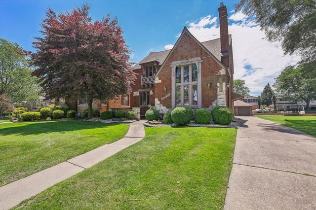 tudor home with a front yard and a garage