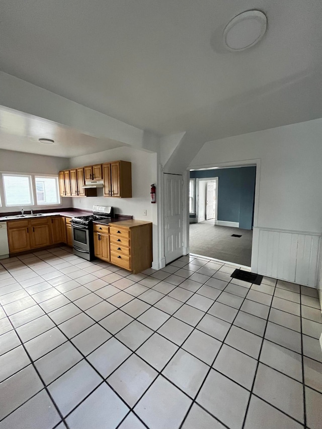 kitchen featuring gas range, dishwasher, sink, and light tile patterned flooring