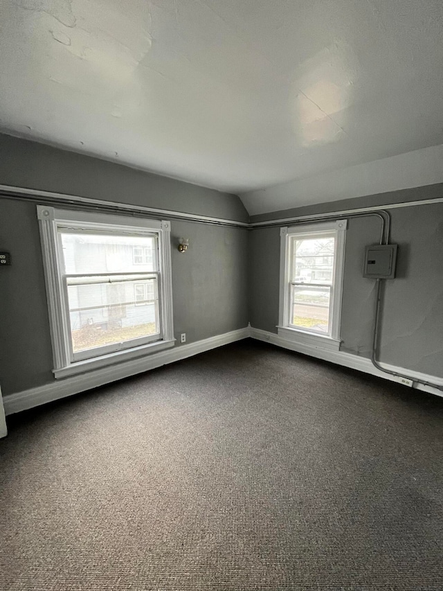 carpeted spare room with vaulted ceiling