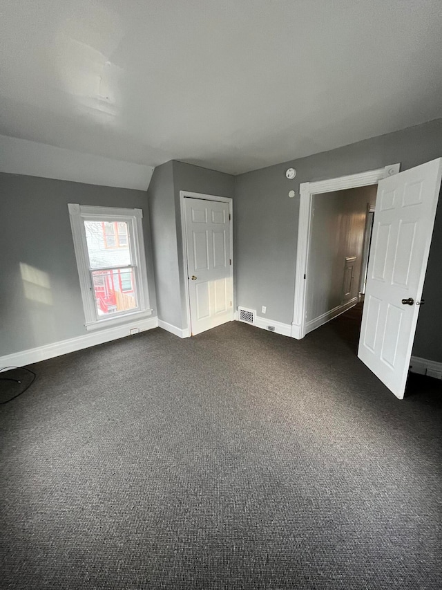 unfurnished room featuring dark colored carpet