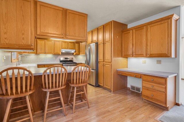 190 Steves Scenic Dr, Horton, MI 49246 - kitchen with a sink, stainless steel appliances, light wood-style flooring, under cabinet range hood, and decorative backsplash