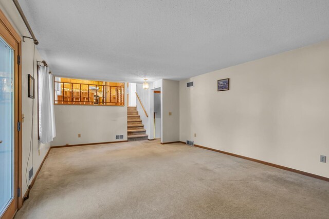 190 Steves Scenic Dr, Horton, MI 49246 - empty room featuring a textured ceiling, stairs, light colored carpet, and baseboards