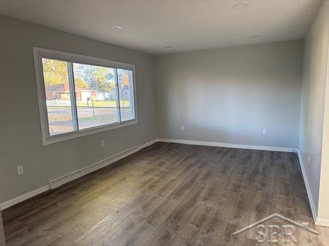 empty room with a baseboard heating unit and dark wood-type flooring