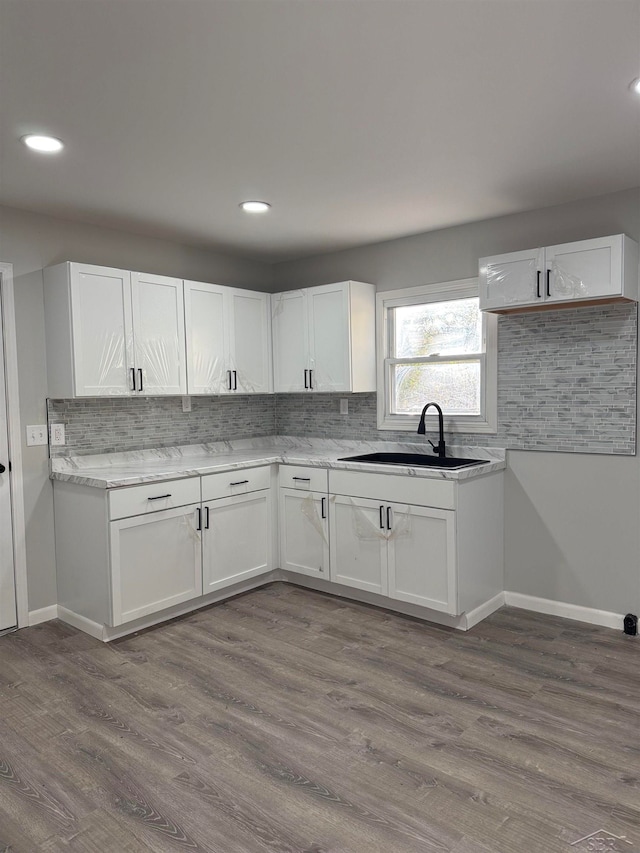 kitchen featuring decorative backsplash, light hardwood / wood-style flooring, white cabinetry, and sink