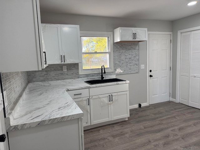 kitchen with sink, decorative backsplash, dark hardwood / wood-style flooring, light stone counters, and white cabinetry