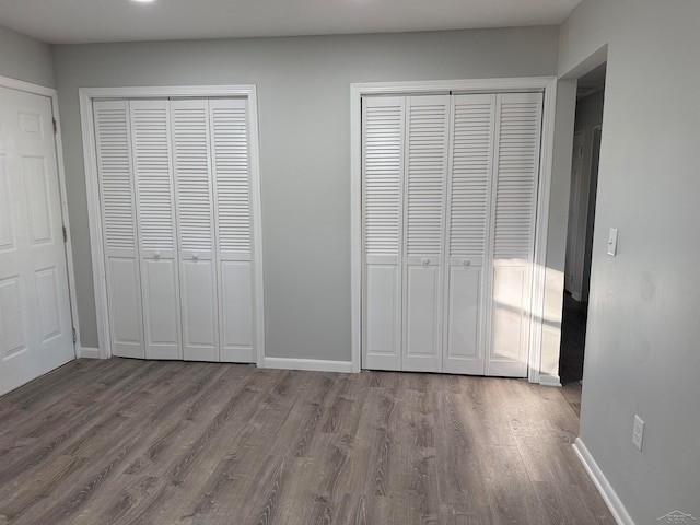 unfurnished bedroom with multiple closets and hardwood / wood-style flooring