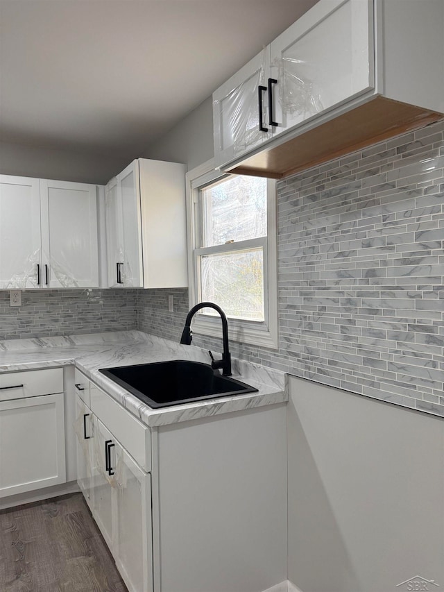 kitchen with white cabinets, dark wood-type flooring, sink, and tasteful backsplash