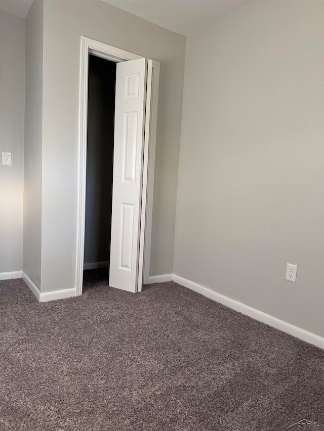 unfurnished bedroom with dark colored carpet and a closet