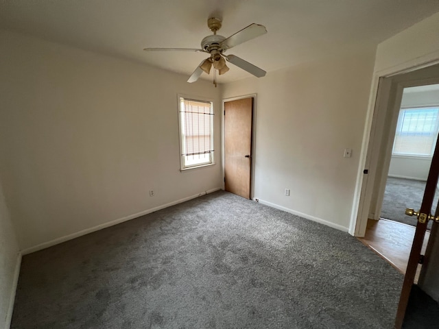 spare room with dark colored carpet and ceiling fan