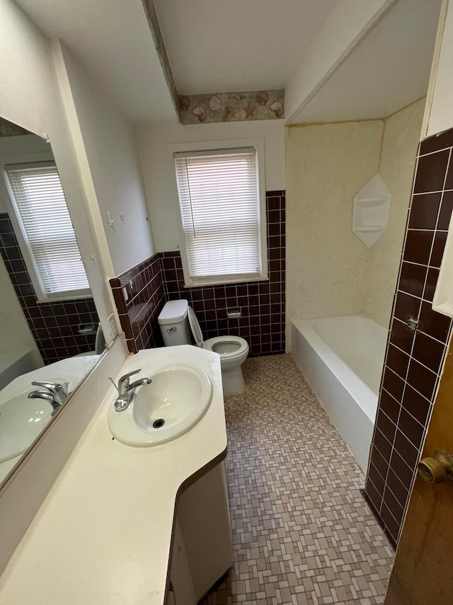 bathroom featuring vanity, toilet, and tile walls