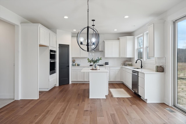 kitchen featuring a kitchen island, appliances with stainless steel finishes, sink, white cabinets, and light wood-type flooring