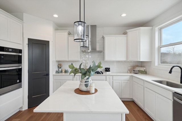 kitchen featuring white cabinetry, a kitchen island, sink, and wall chimney exhaust hood