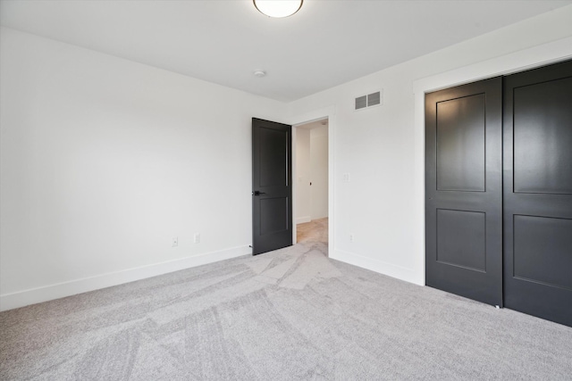 unfurnished bedroom with light carpet and a closet