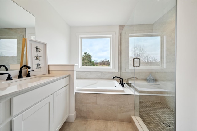 bathroom with vanity, tiled tub, plenty of natural light, and tile patterned floors