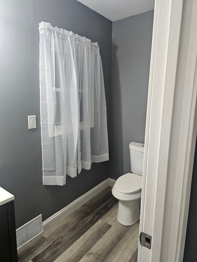 bathroom featuring wood-type flooring, vanity, and toilet