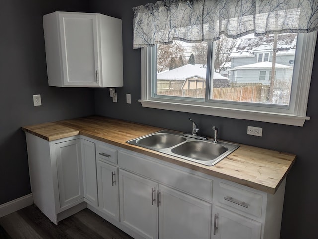 kitchen with white cabinetry, sink, and wooden counters