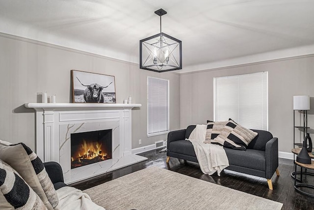 living room featuring a notable chandelier, dark wood-type flooring, and a high end fireplace