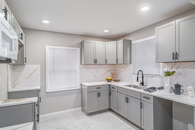 kitchen with gray cabinets, sink, and tasteful backsplash