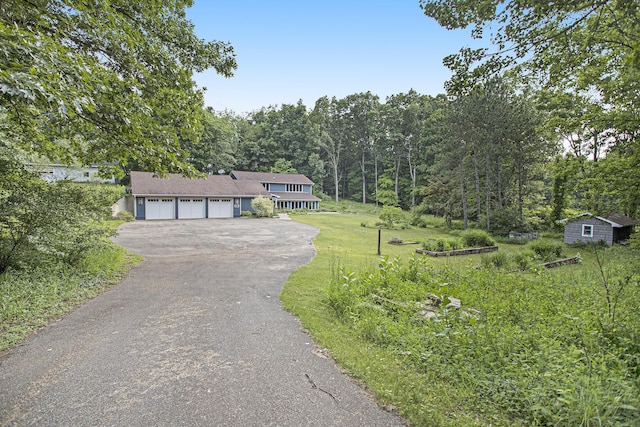 16460 15 Mile Rd, Marshall, MI 49068 - tri-level home with asphalt driveway, a front lawn, a garage, a storage shed, and a wooded view