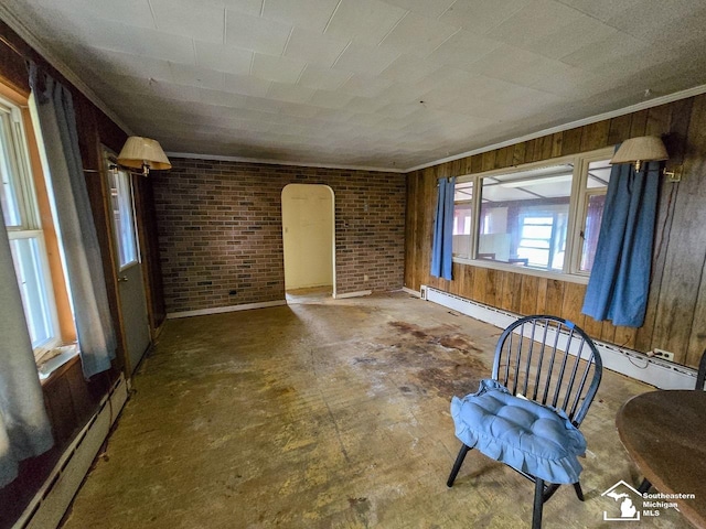 unfurnished room with wood walls, ornamental molding, brick wall, and a baseboard radiator