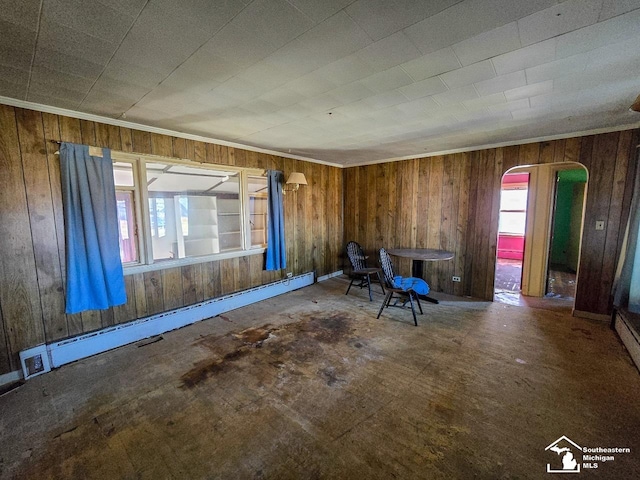 interior space featuring baseboard heating, wood walls, and plenty of natural light