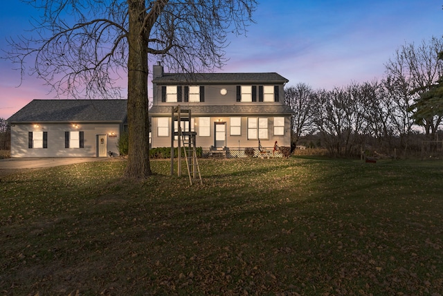 back house at dusk featuring a yard