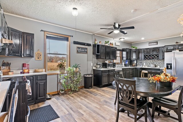 kitchen with ceiling fan, ornamental molding, light wood-type flooring, a textured ceiling, and stainless steel appliances