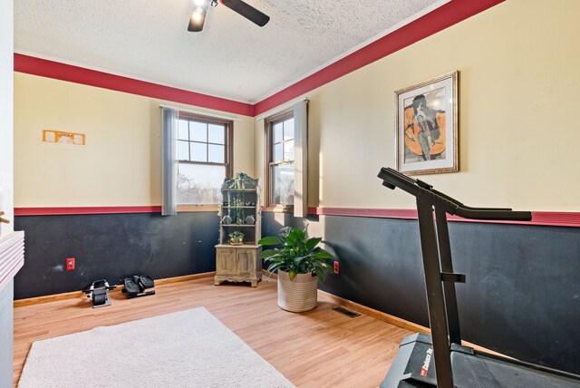 workout room with ceiling fan, a textured ceiling, and hardwood / wood-style flooring