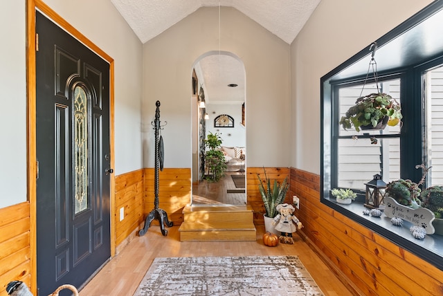 foyer entrance with lofted ceiling, light hardwood / wood-style floors, and a textured ceiling