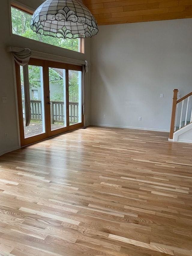 interior space with light hardwood / wood-style flooring, a towering ceiling, and wood ceiling