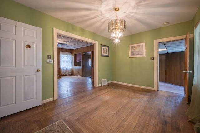 interior space with dark wood-type flooring, a drop ceiling, and a notable chandelier