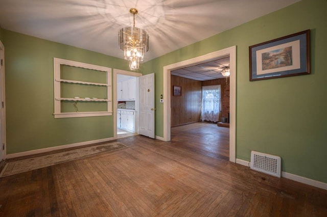 unfurnished dining area with parquet flooring, built in features, and a notable chandelier