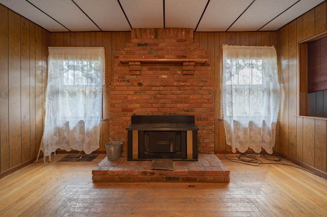 unfurnished living room with light hardwood / wood-style floors, a fireplace, and wooden walls