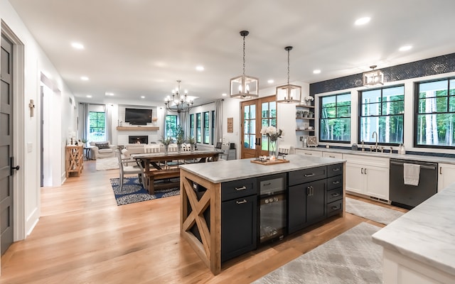 kitchen with dishwasher, a center island, hanging light fixtures, light hardwood / wood-style flooring, and white cabinetry