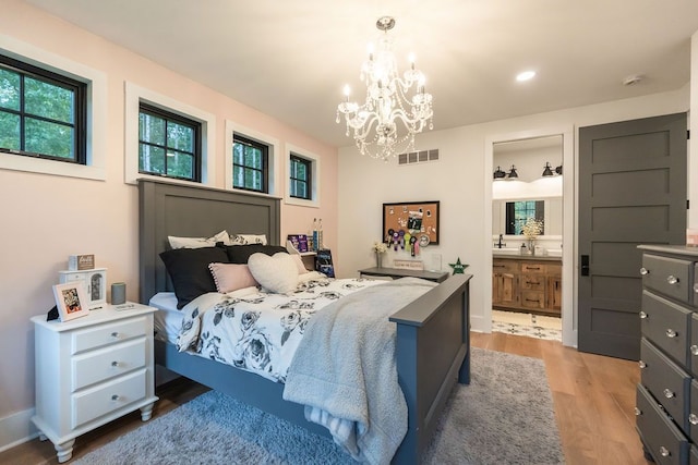 bedroom with hardwood / wood-style floors, ensuite bathroom, a notable chandelier, and sink