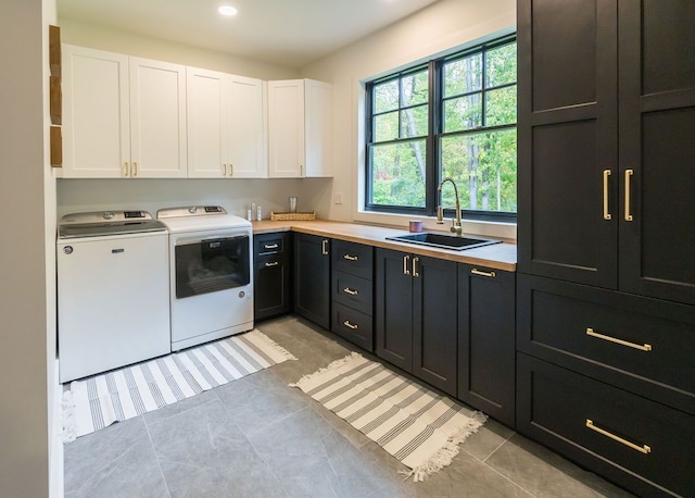 laundry area featuring washer and dryer, cabinets, light tile patterned floors, and sink