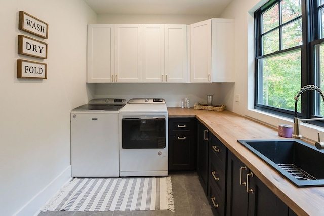 laundry area featuring cabinets, washing machine and clothes dryer, a wealth of natural light, and sink