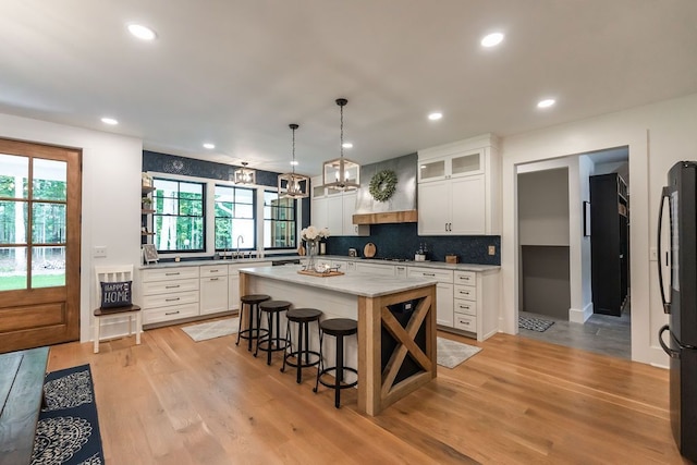 kitchen featuring white cabinets, a center island, a wealth of natural light, and hanging light fixtures