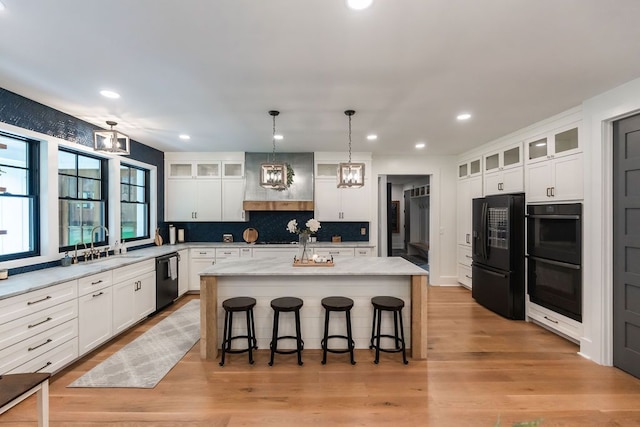 kitchen featuring white cabinets, a center island, and black appliances