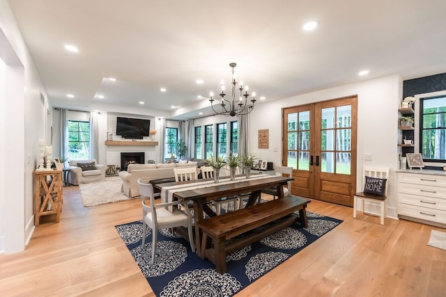 dining space featuring french doors, light hardwood / wood-style floors, and an inviting chandelier