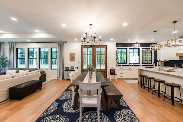 dining room with sink, a chandelier, french doors, and light wood-type flooring