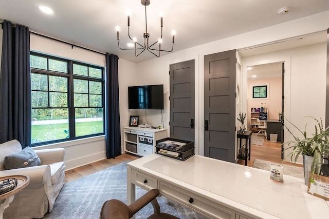 home office with an inviting chandelier and light hardwood / wood-style flooring