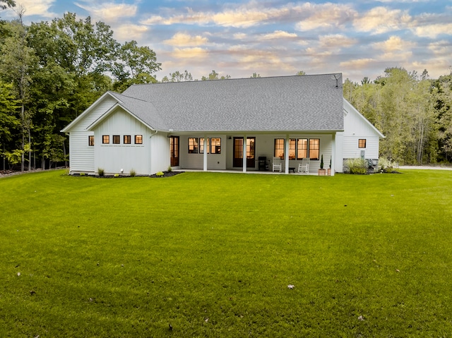 back house at dusk featuring a yard