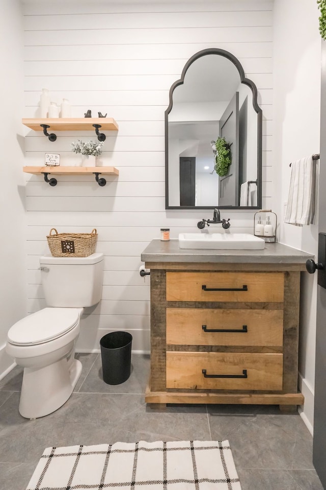 bathroom with tile patterned floors, vanity, toilet, and wooden walls