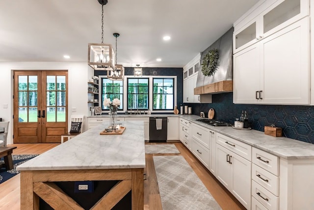 kitchen featuring french doors, white cabinets, light stone countertops, black dishwasher, and a kitchen island