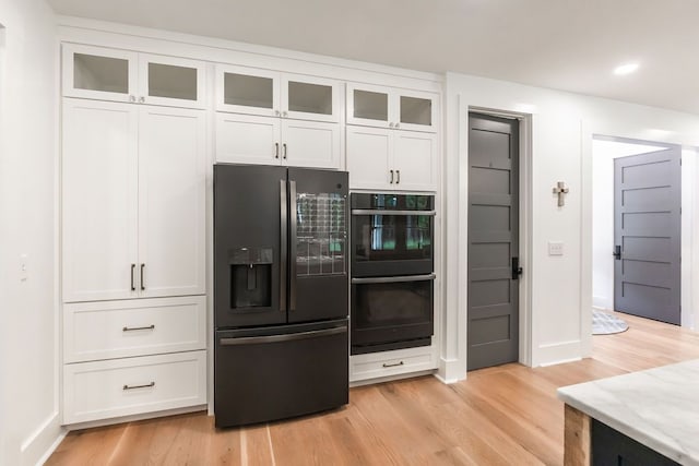 kitchen with black appliances, white cabinets, and light wood-type flooring